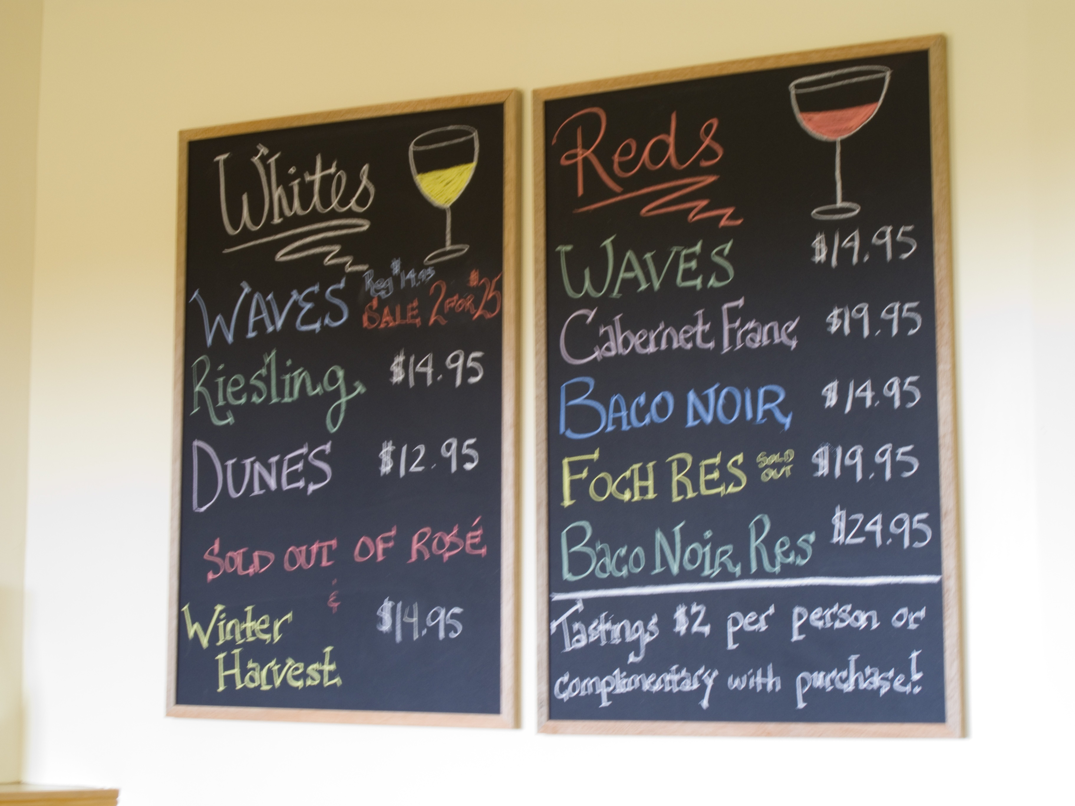 Ardoise des prix des vins blancs et rouges affichee dans un restaurant avec tarifs au verre