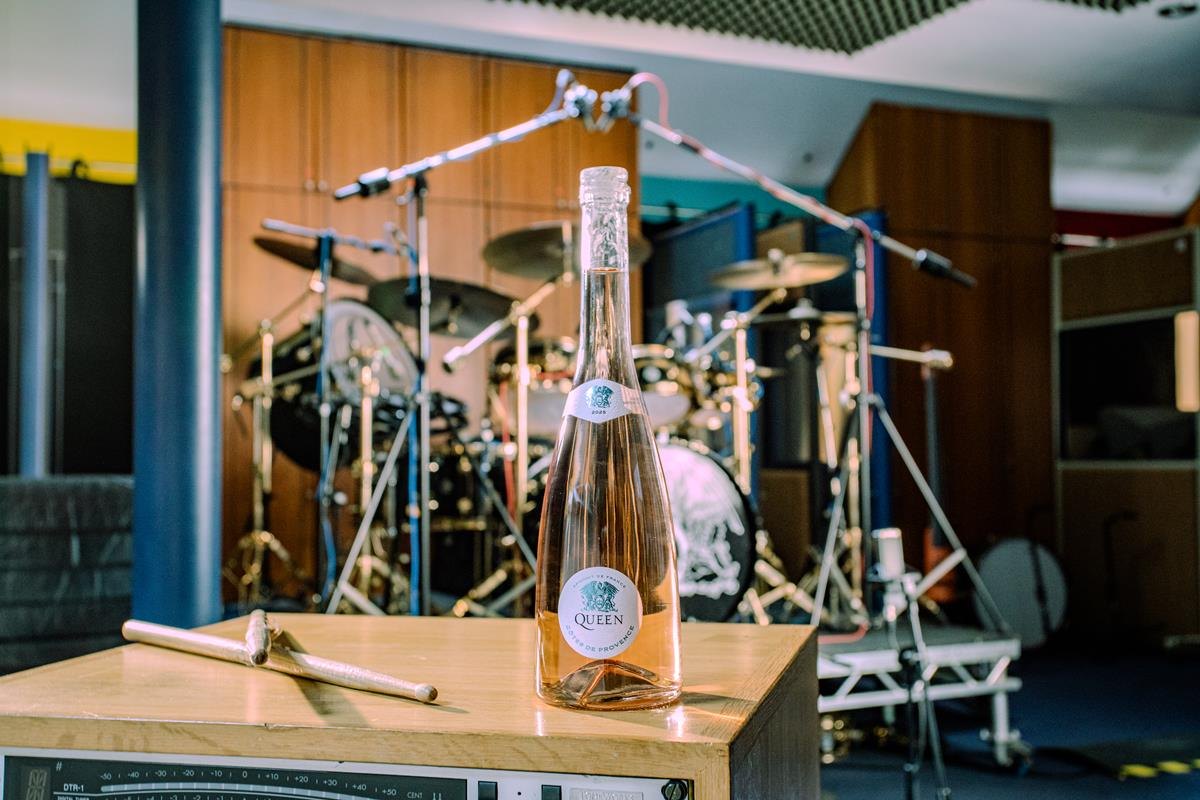Bouteille de rosé Queen Côtes de Provence posée sur un ampli devant la batterie de Roger Taylor en studio