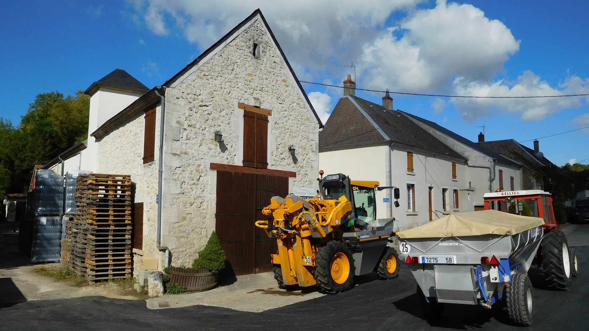 Machine à vendanger accompagnée d'un tracteur et d'une remorque dans un vignoble