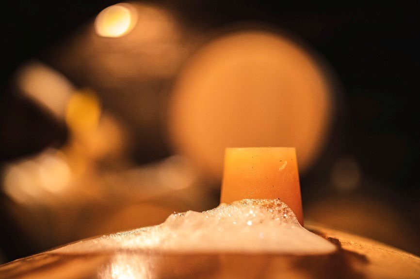 Fût en fermentation dans une cave bourguignonne, mousse à la bonde
