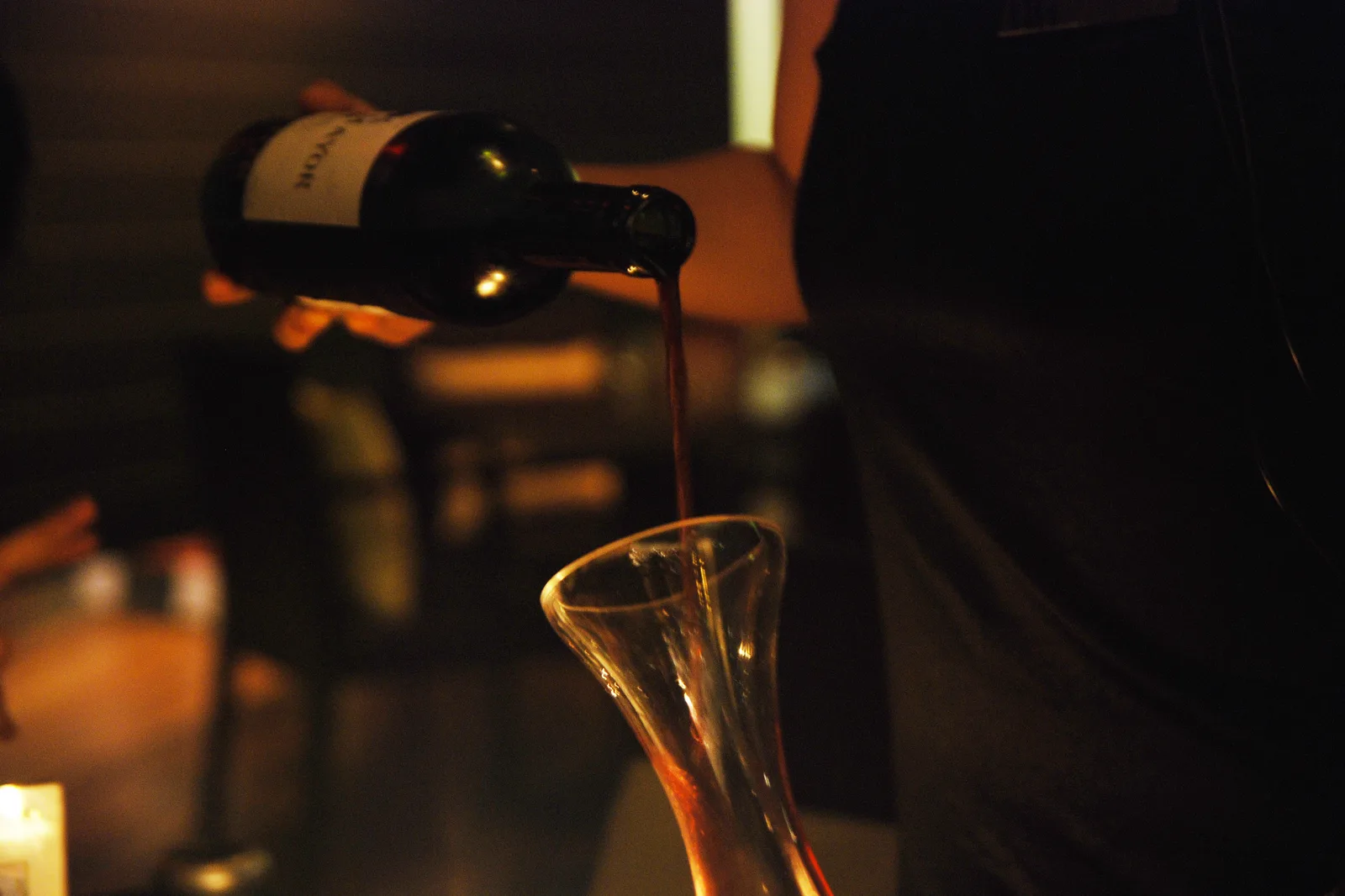Vin rouge versé lentement d’une bouteille dans une carafe en verre