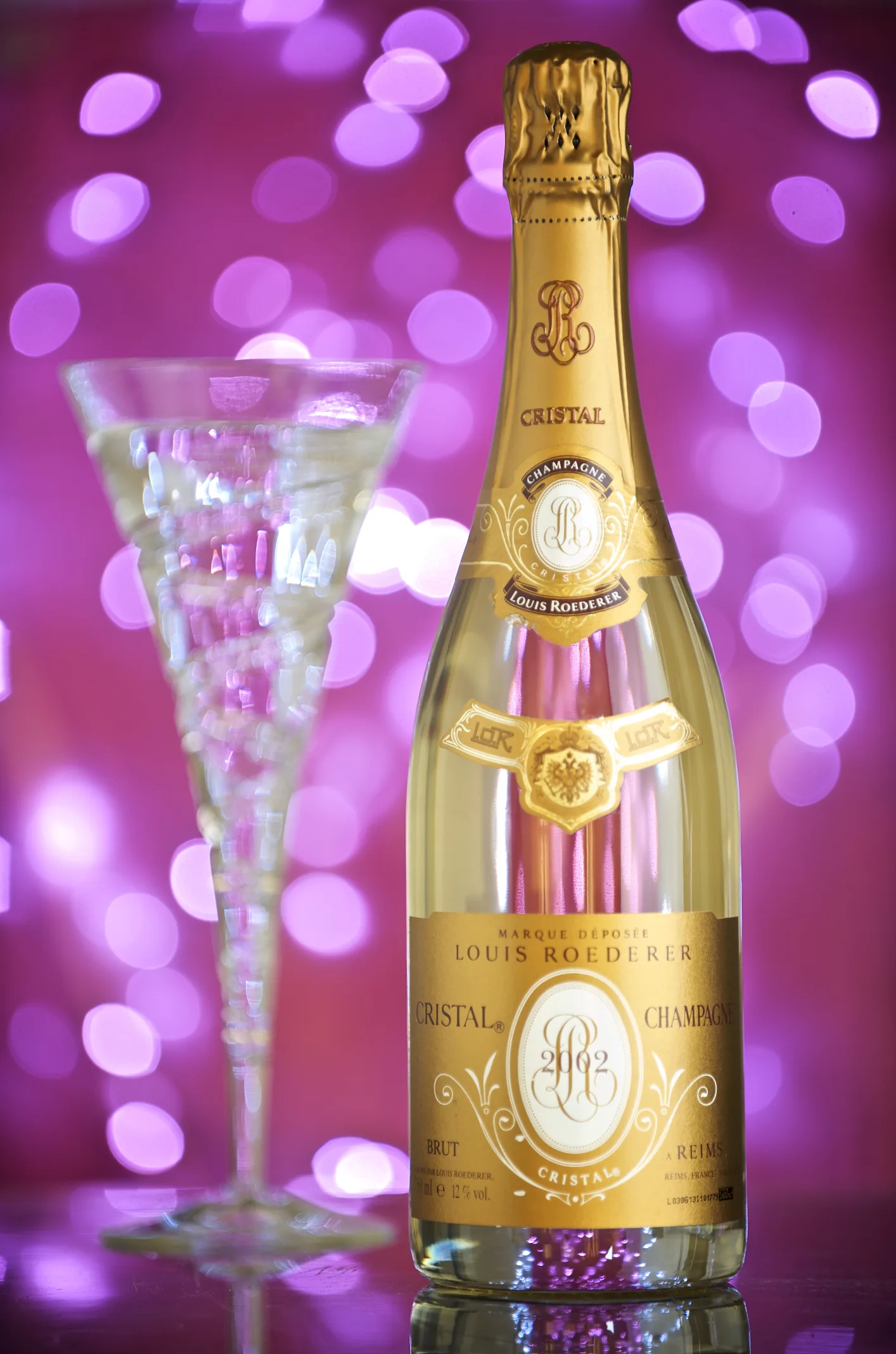 Bouteille de champagne Cristal de Louis Roederer en verre transparent à côté d'une flûte