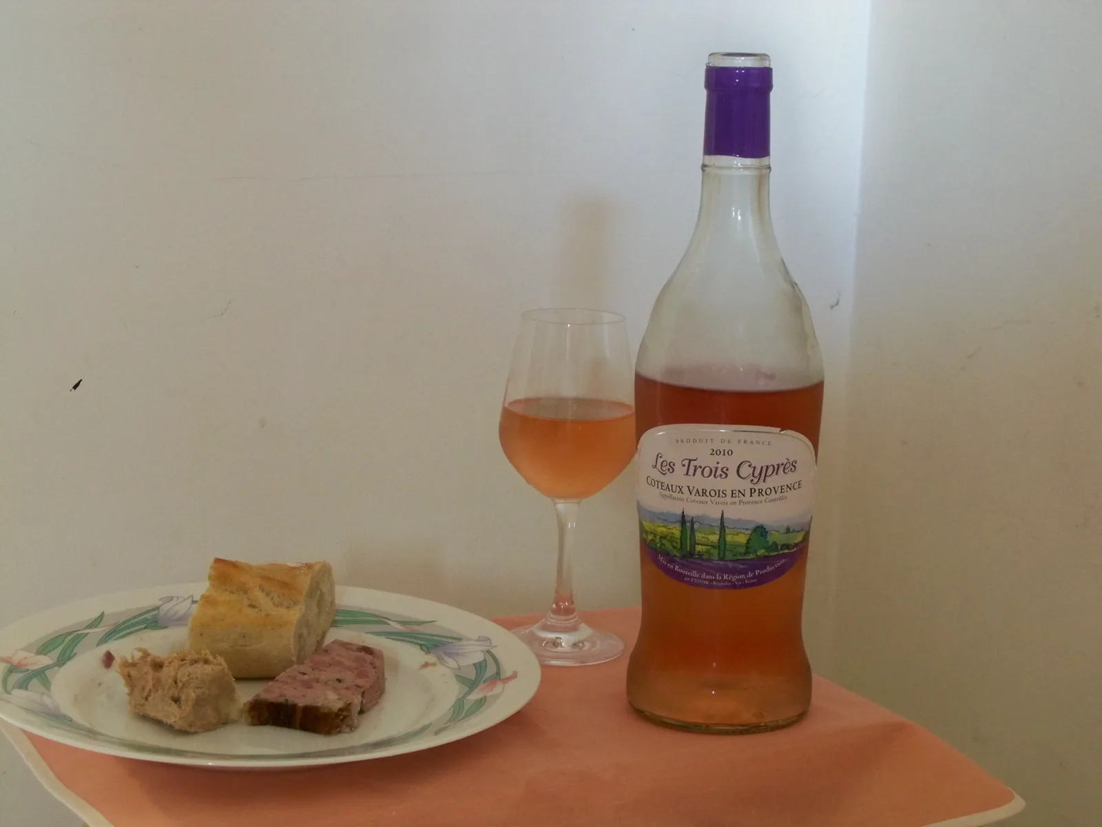 Bouteille de rosé de Provence en verre transparent posée sur une table à côté d'un verre de rosé