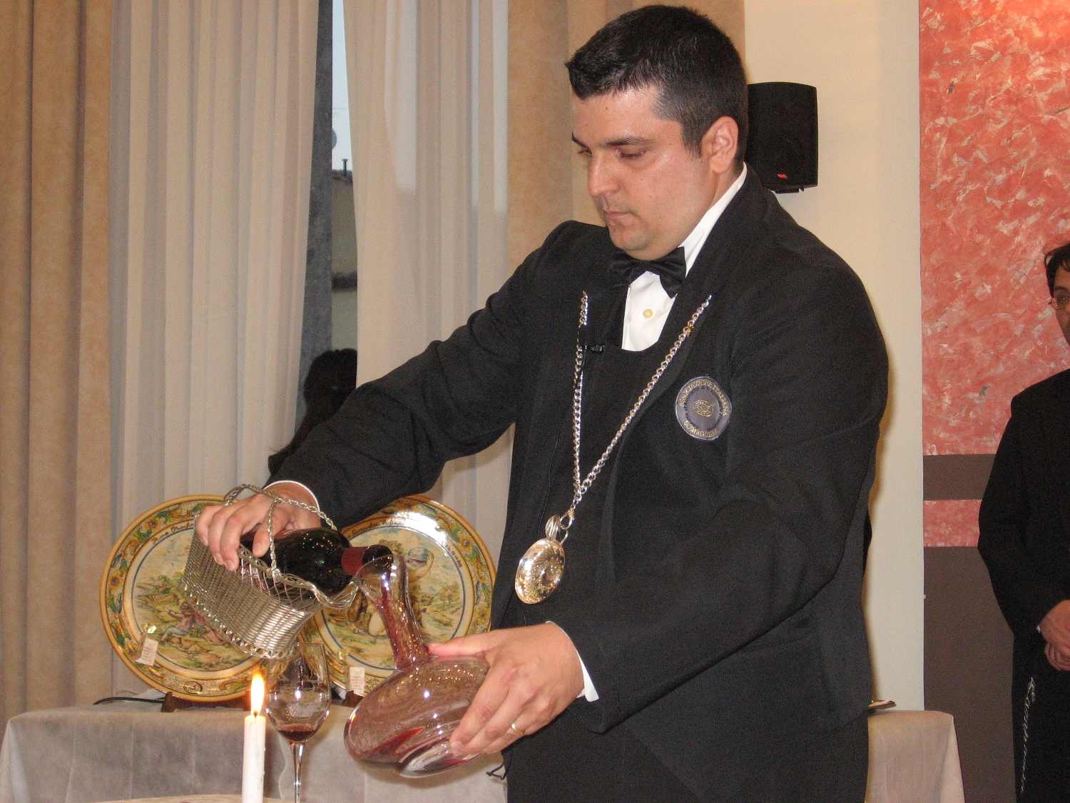 Sommelier qui carafe et sert un vin rouge à table dans un restaurant